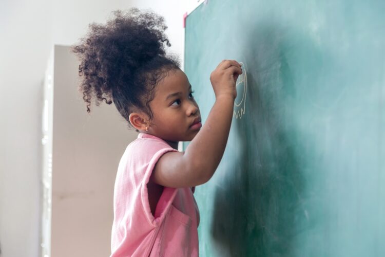 Fillette qui écrit au tableau à l'école